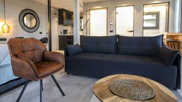 Una sala de estar moderna con un sillón de cuero, un sofá oscuro y una mesa de centro de madera.