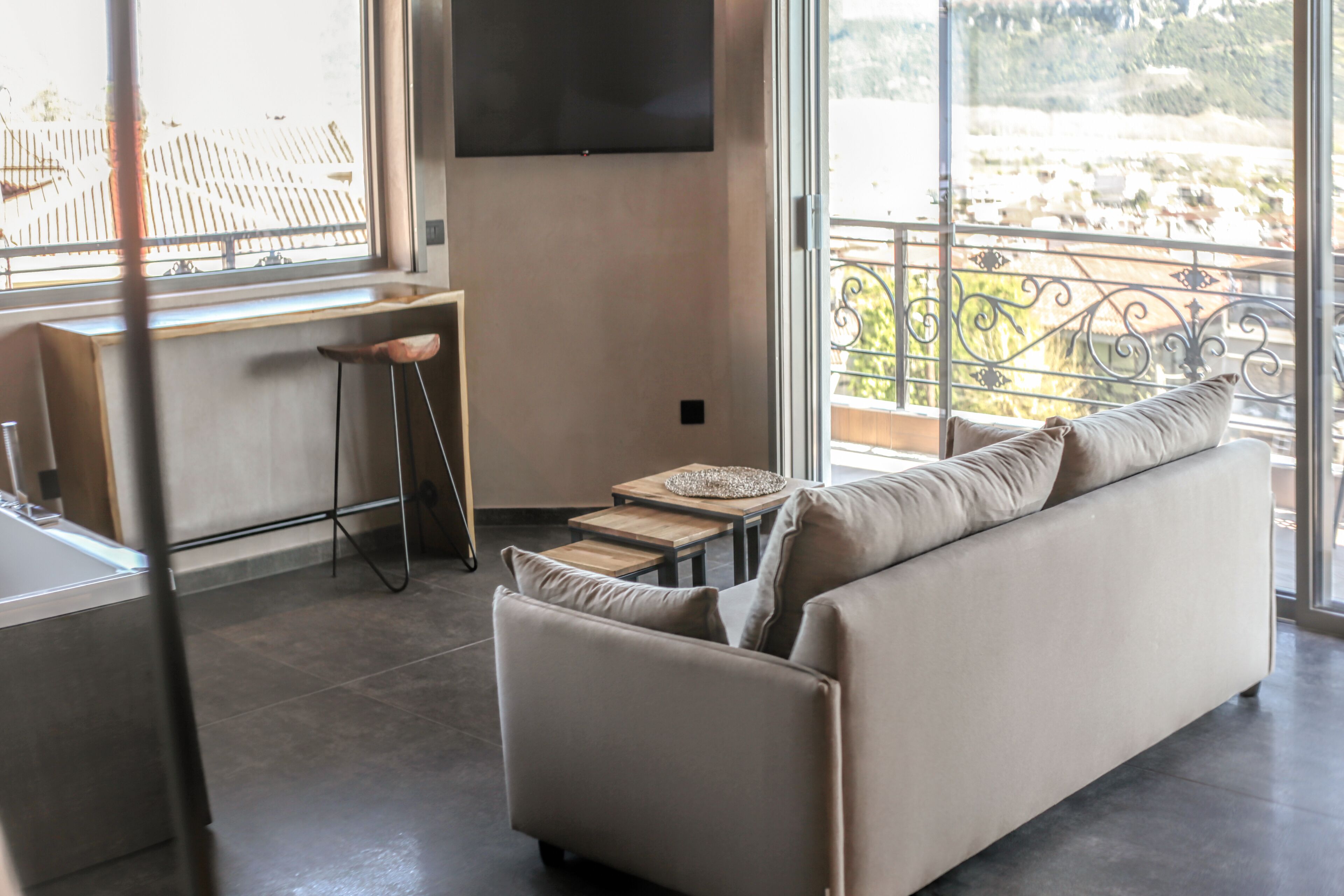 A modern living room with a sofa, a small table, and a TV mounted on the wall.