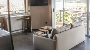 A modern living room with a sofa, a small table, and a TV mounted on the wall.