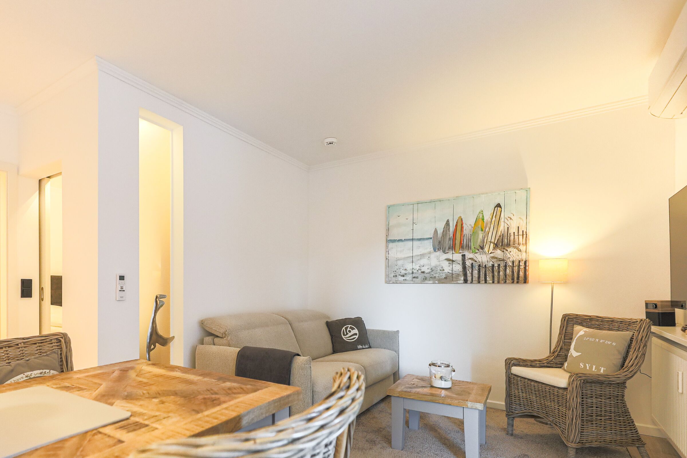 Ein gemütliches Wohnzimmer mit einer Couch, einem Esstisch und einem Bild an der Wand.