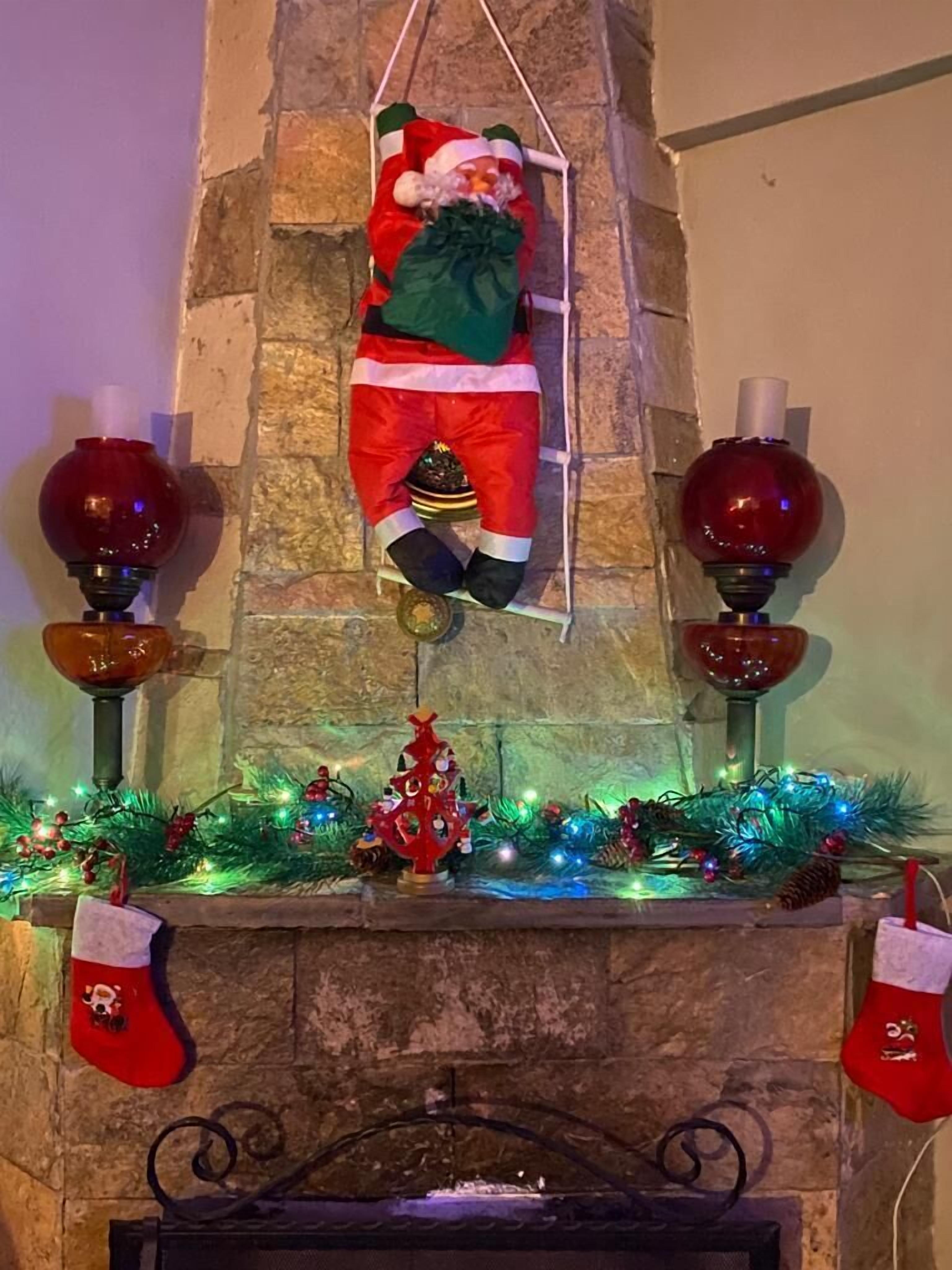 A fireplace with a Santa Claus decoration, a small Christmas tree, and stockings.