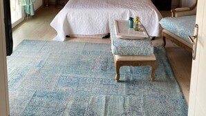 A bedroom with a large bed, a canopy, a bedside table with a lamp, a chair, and a small table with a vase. - PALMİYE PANSİYON (Karaburun)