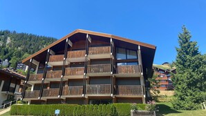 Un hotel a più piani con balconi in legno e montagne sullo sfondo.