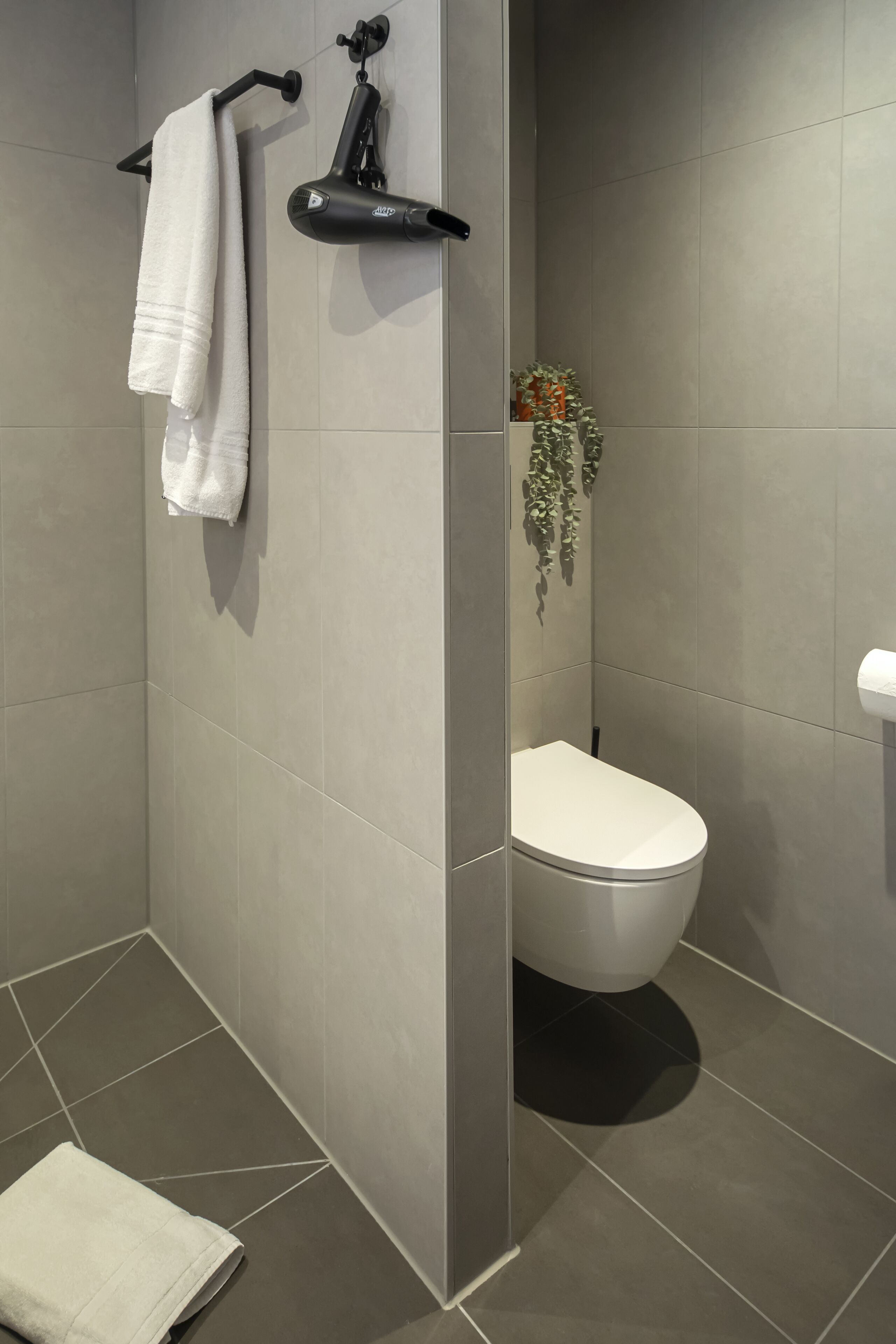A modern bathroom with a toilet, a towel rack, and a shower area.
