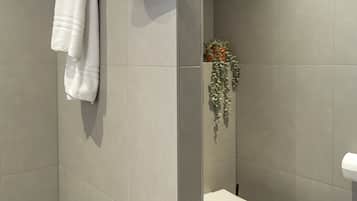 A modern bathroom with a toilet, a towel rack, and a shower area.