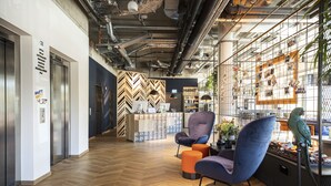 A modern interior with a herringbone wood floor, a seating area with purple chairs, and a market display. - Loginn Hotel Waiblingen (Waiblingen)