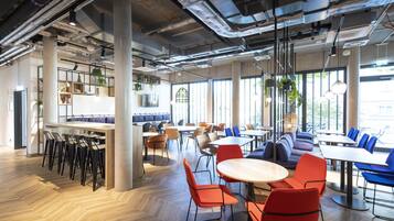 A modern dining area with high ceilings, exposed ductwork, and large windows.