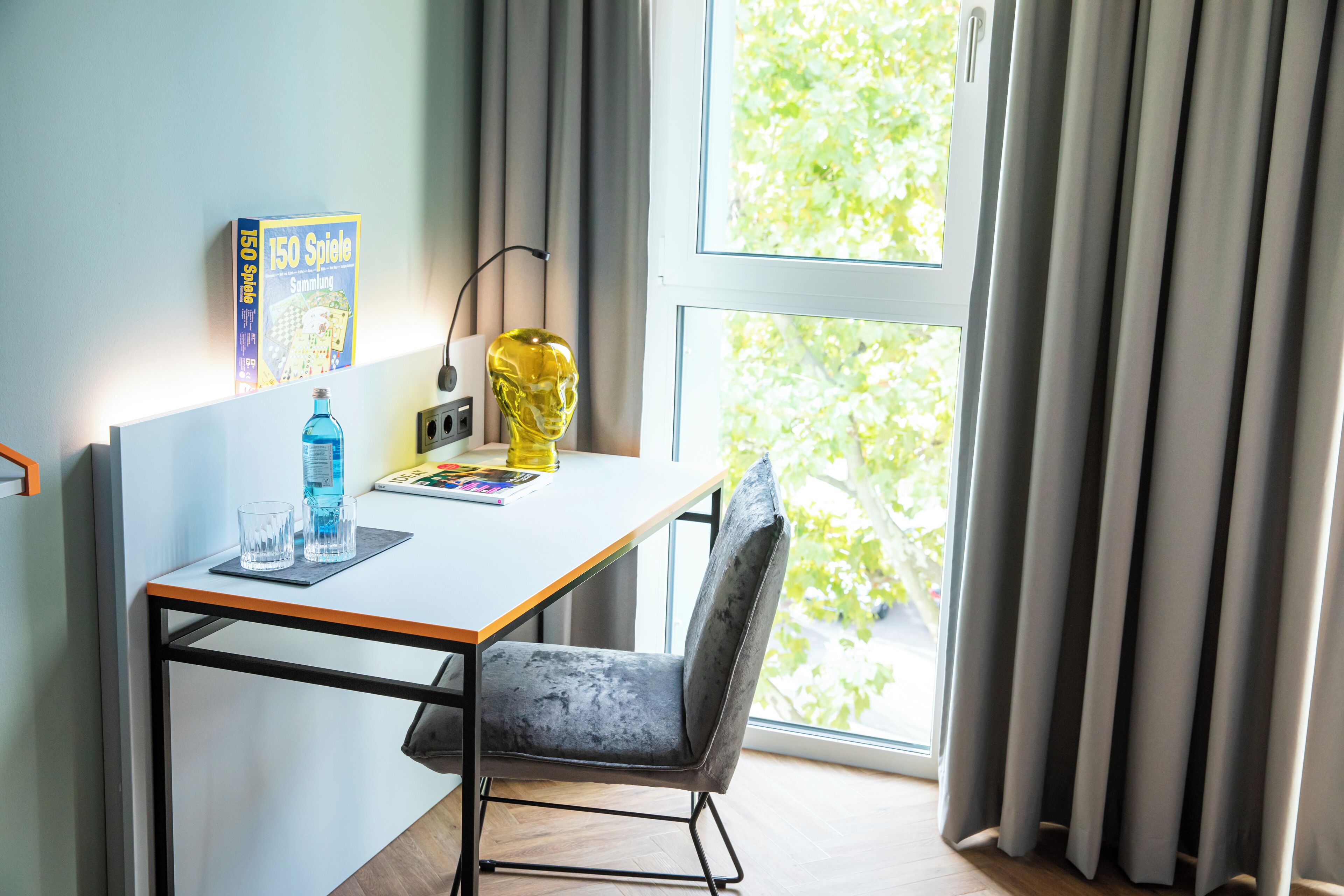 A modern office space with a white desk, a chair, a water bottle, a magazine, and a decorative skull.