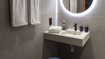 Ein modernes Badezimmer mit einem weißen Waschbecken, einem runden Spiegel und einer blauen Toilette.
