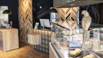Une vitrine de boulangerie présentant des pâtisseries et ornée d’un oiseau décoratif.