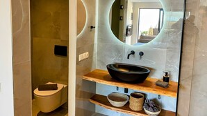 Une salle de bain moderne avec un grand miroir, un lavabo noir et des étagères en bois.
