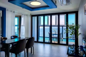 A modern room with a large sliding glass door leading to a balcony with a view of the sea. - Siesta (Namhae)