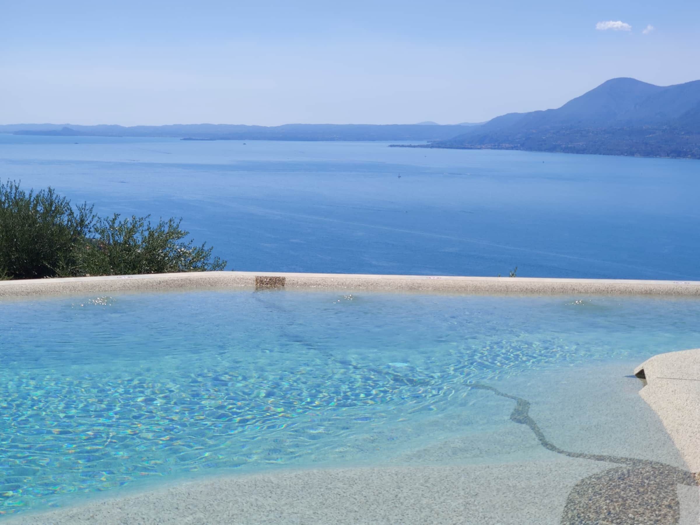 A clear blue pool with a view of a distant mountain and the sea.