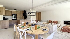 Eine moderne Küche mit Holzschränken und einem Essbereich mit einem runden Tisch und weißen Stühlen.