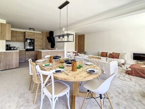Een moderne keuken met houten kastjes en een eethoek met een ronde tafel en witte stoelen.
