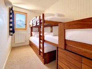 Een slaapkamer met stapelbed en uitzicht op een berg.