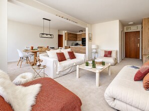 Een moderne woonkamer met een bank, een eettafel en een keuken op de achtergrond.