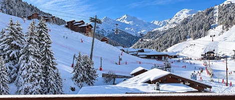 A snow-covered mountain resort with ski lifts, wooden cabins, and a clear blue sky.