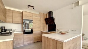 Eine moderne Küche mit Holzausstattung, einem Edelstahlkühlschrank und einer weißen Arbeitsplatte.