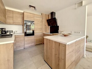 Een moderne keuken met houten kastjes, een roestvrijstalen koelkast en een wit aanrecht.