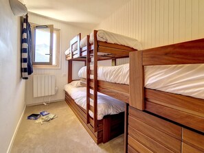Een kamer met drie stapelbedden, een raam met uitzicht en een radiator.