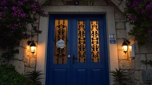 A stone building with a blue door, two potted plants, and a sign above the door. - Pürlen Otel Alaçatı (Cesme)