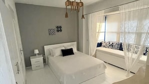 A bedroom with a bed, bedside table, and a window with curtains. - Pürlen Otel Alaçatı (Cesme)