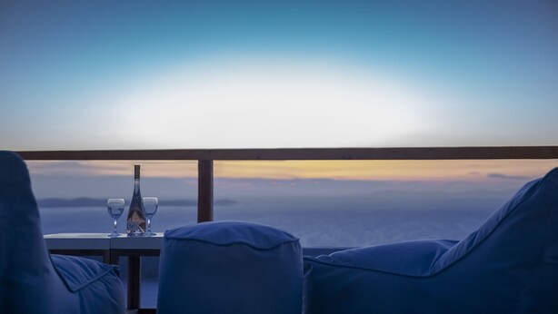 A balcony with a table set for two, overlooking a scenic view. - Villa Cataleya (Μύκονος)