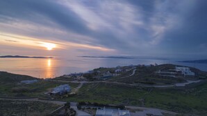 A coastal town with white buildings, a clear view of the sea, and a winding road. - Villa Cataleya (Μύκονος)