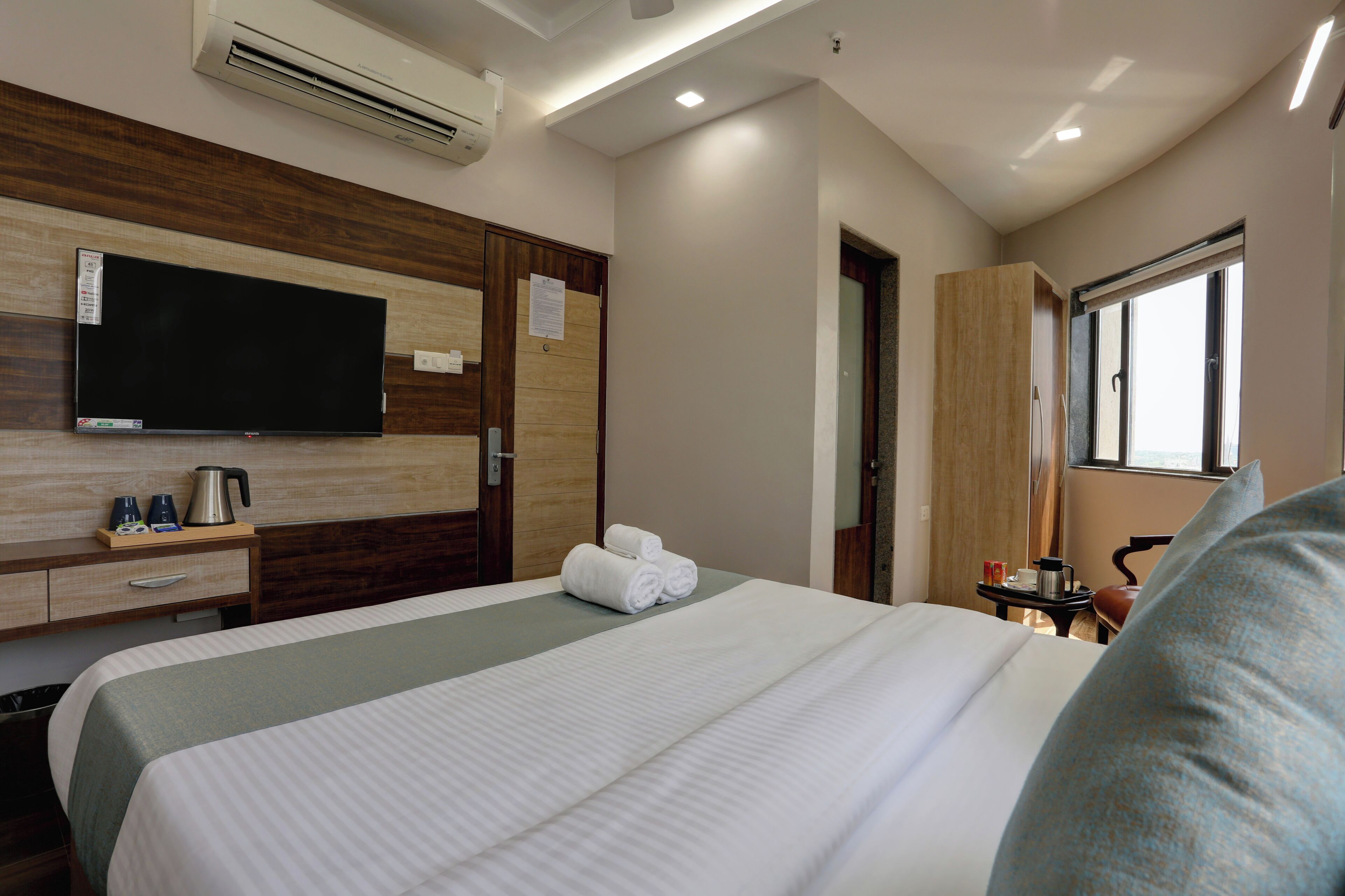 A hotel room with a bed, a flat-screen TV, a coffee maker, and a window.