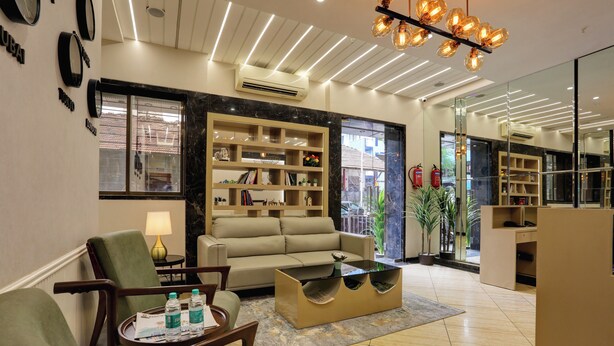 Un moderno vestíbulo de hotel con un sofá, sillones, una mesa de centro y una estantería.