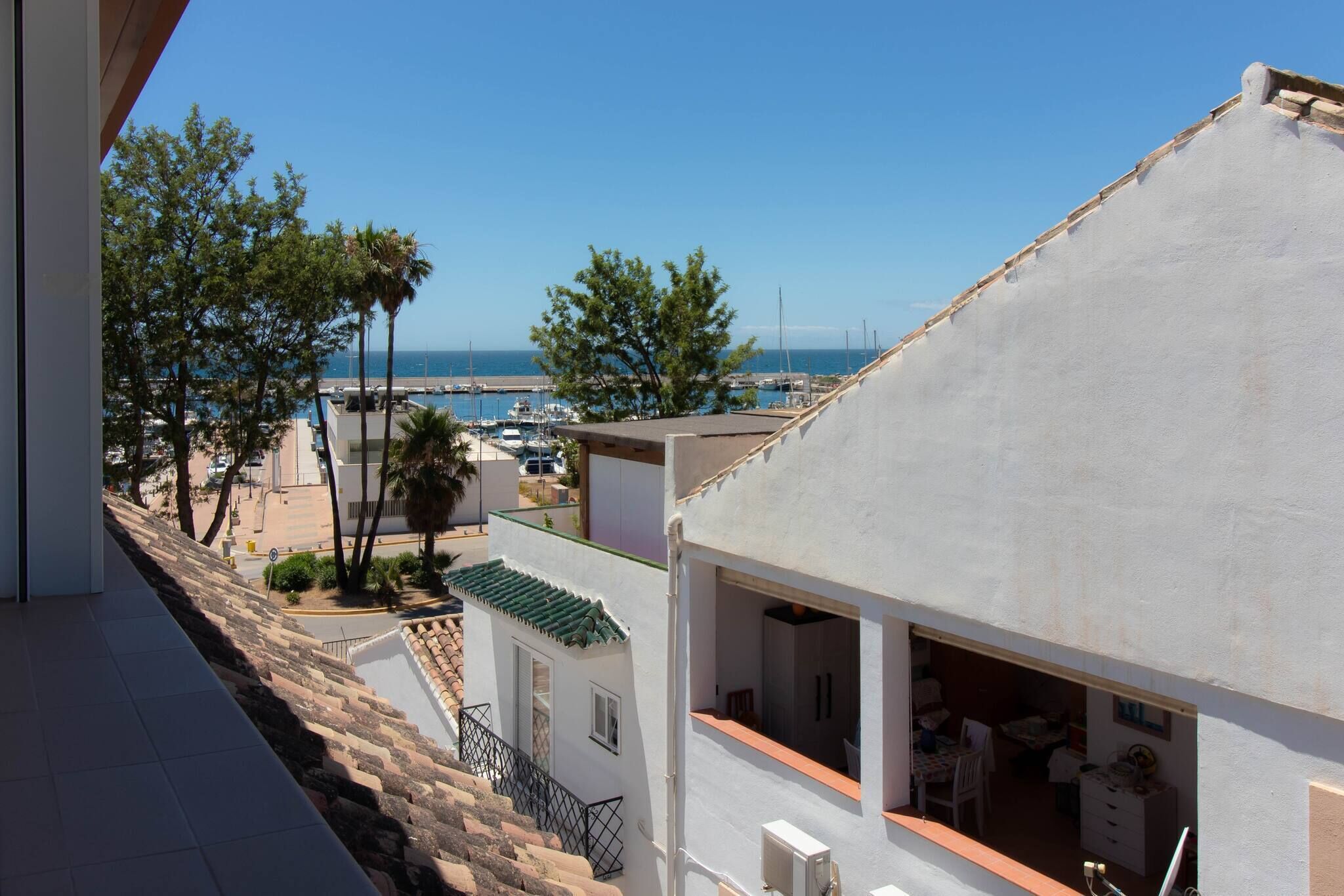 A coastal property with a balcony overlooking a marina and the sea.