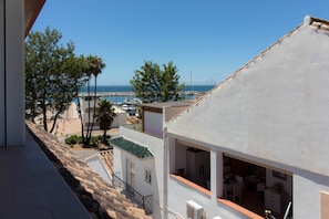 Une propriété située sur la côte, dotée d’un balcon offrant une vue sur un port de plaisance et la mer.