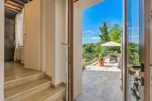 A staircase leading to a balcony with a view of a garden and outdoor furniture.