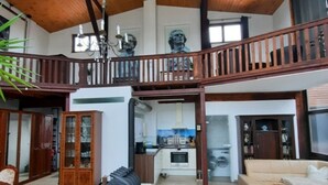 A spacious living area with a high ceiling, wooden beams, a balcony, a kitchen in the background, and a large cabinet. - Außergewöhnlich Wohnen in Weimar (Weimar)