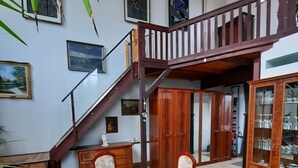 A dining area with a wooden table and chairs, a staircase, and a cabinet with glass doors. - Außergewöhnlich Wohnen in Weimar (Weimar)