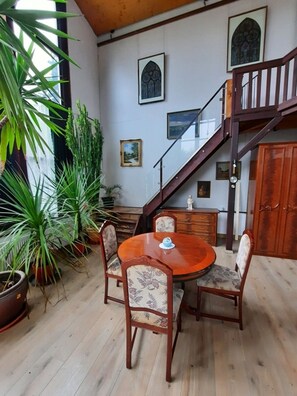 A dining area with a wooden table and chairs, surrounded by potted plants. - Außergewöhnlich Wohnen in Weimar (Weimar)