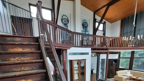 A spacious living area with a wooden staircase, a dining table with chairs, and a view of the outdoors. - Außergewöhnlich Wohnen in Weimar (Weimar)