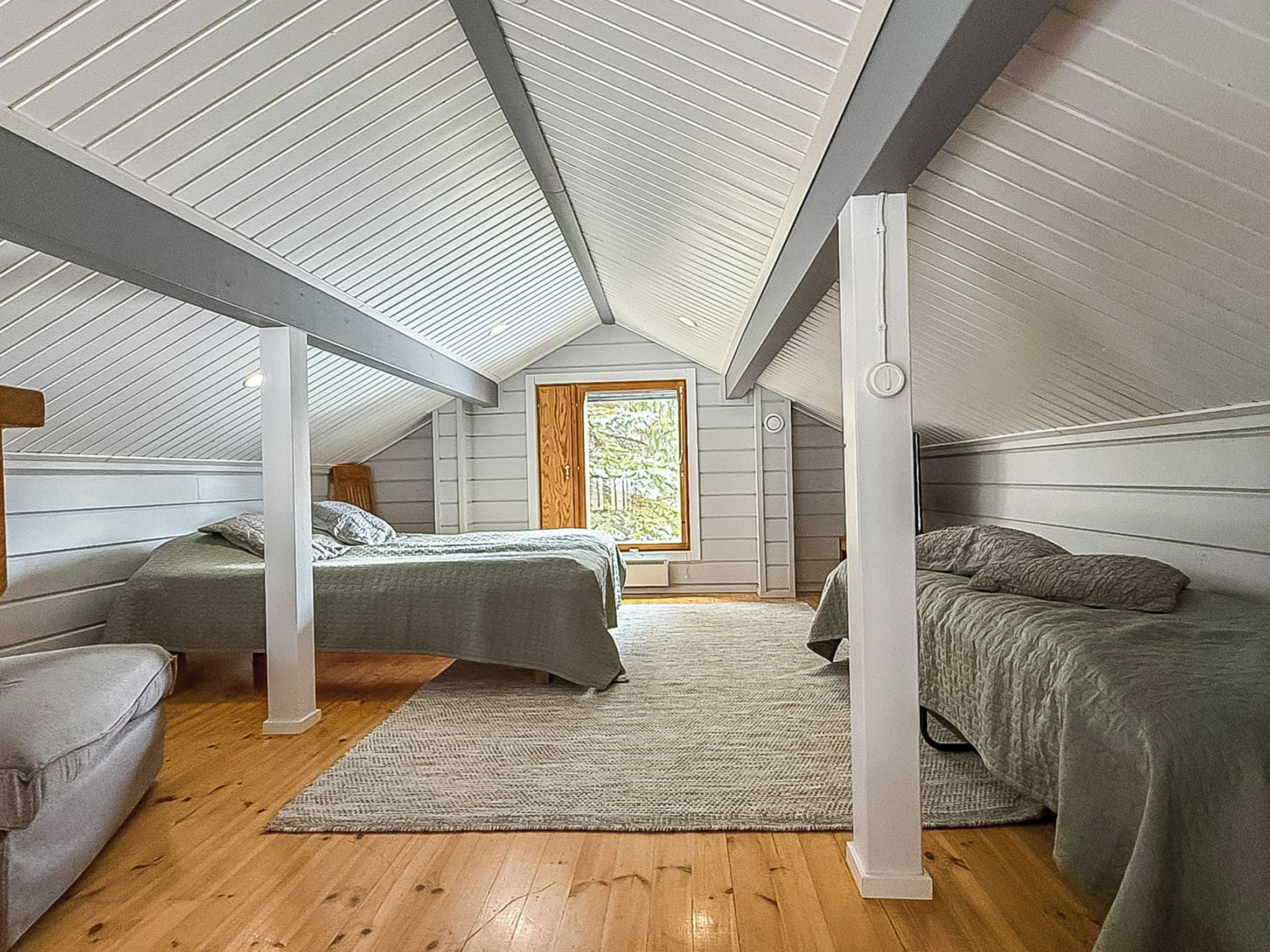 Una habitación con dos camas, una ventana y piso de madera.