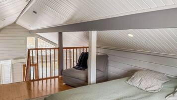 Una habitación con techo inclinado, una cama, una silla y una mesa.