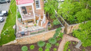 A two-story brick building with a red roof, a balcony, and a stone wall.