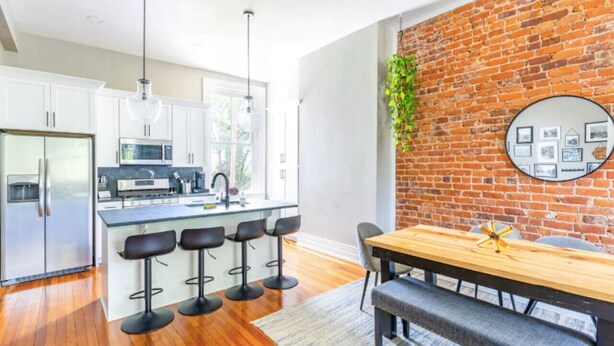 A modern kitchen with white cabinets, a stainless steel refrigerator, and a central island with bar stools.