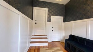 A hallway with a staircase, a bench, and patterned walls.