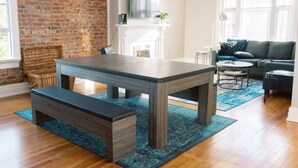 A modern living room with a wooden dining table, bench, and a blue rug. - 2 King Beds - Pool Table, Heart of Downtown LYH (Lynchburg)