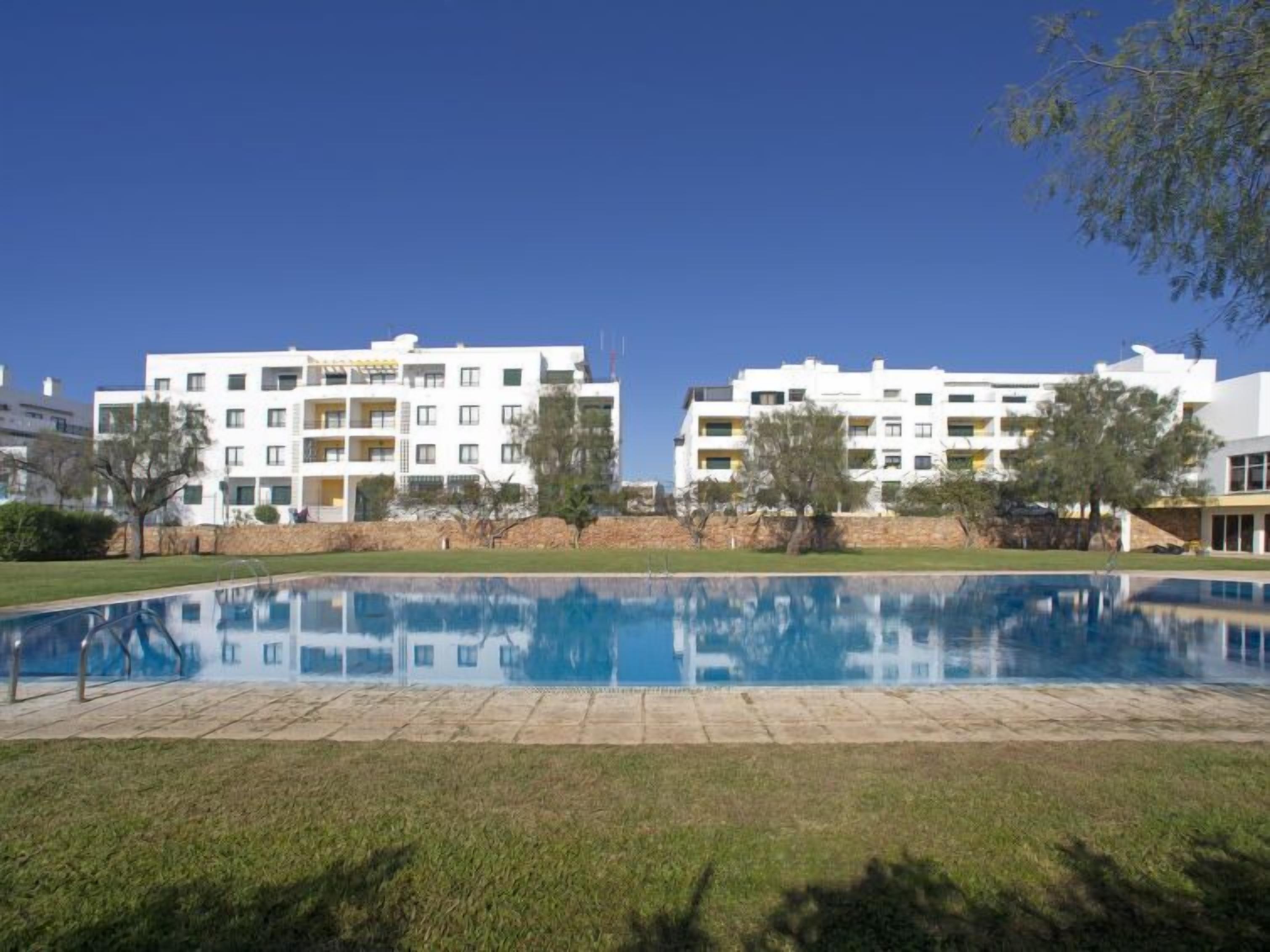 Un moderno complejo de apartamentos con piscina al frente.
