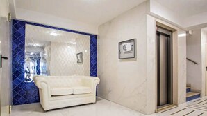 Ein modernes Interieur mit einem weißen Sofa, einer Wand mit blauen Fliesen und einem gerahmten Bild.