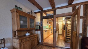 Een rustieke keuken met houten keukenkastjes, een houten bankje en een deur naar een eetgedeelte.