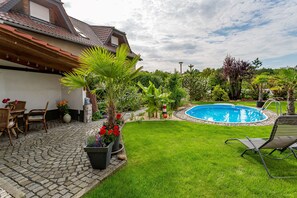 Un jardin avec une piscine, une terrasse en bois et une grande variété de plantes et de fleurs.