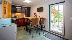 Een functionele keuken met een eethoek, een aan de muur bevestigde televisie en uitzicht door de deur.
