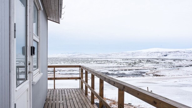 Eine Holzterrasse führt zu einem Gebäude mit Blick auf eine verschneite Landschaft.